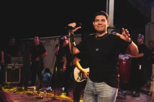 Kbeto Zuleta sonríe con el micrófono en una mano y saluda al público durante una presentación.